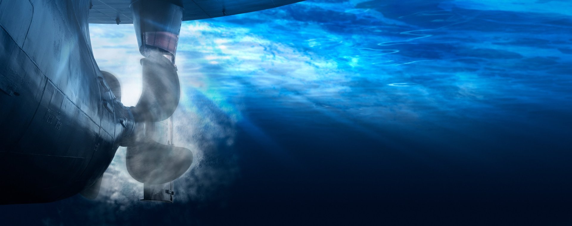 Underwater view of a ship propeller and rudder in clear water