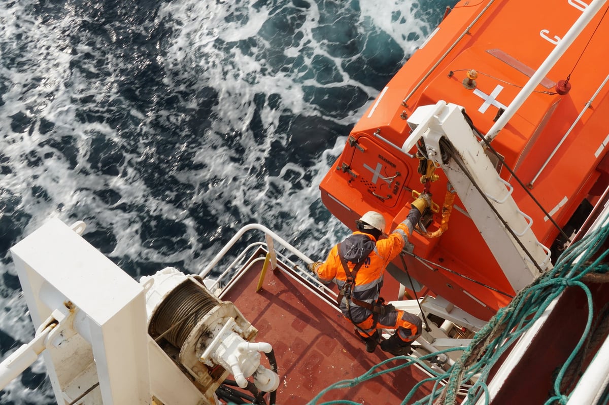 Crew member in safety harness working on vessel equipment